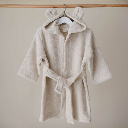 Mushie Bear Robe Beige on a hanger against a beige wall