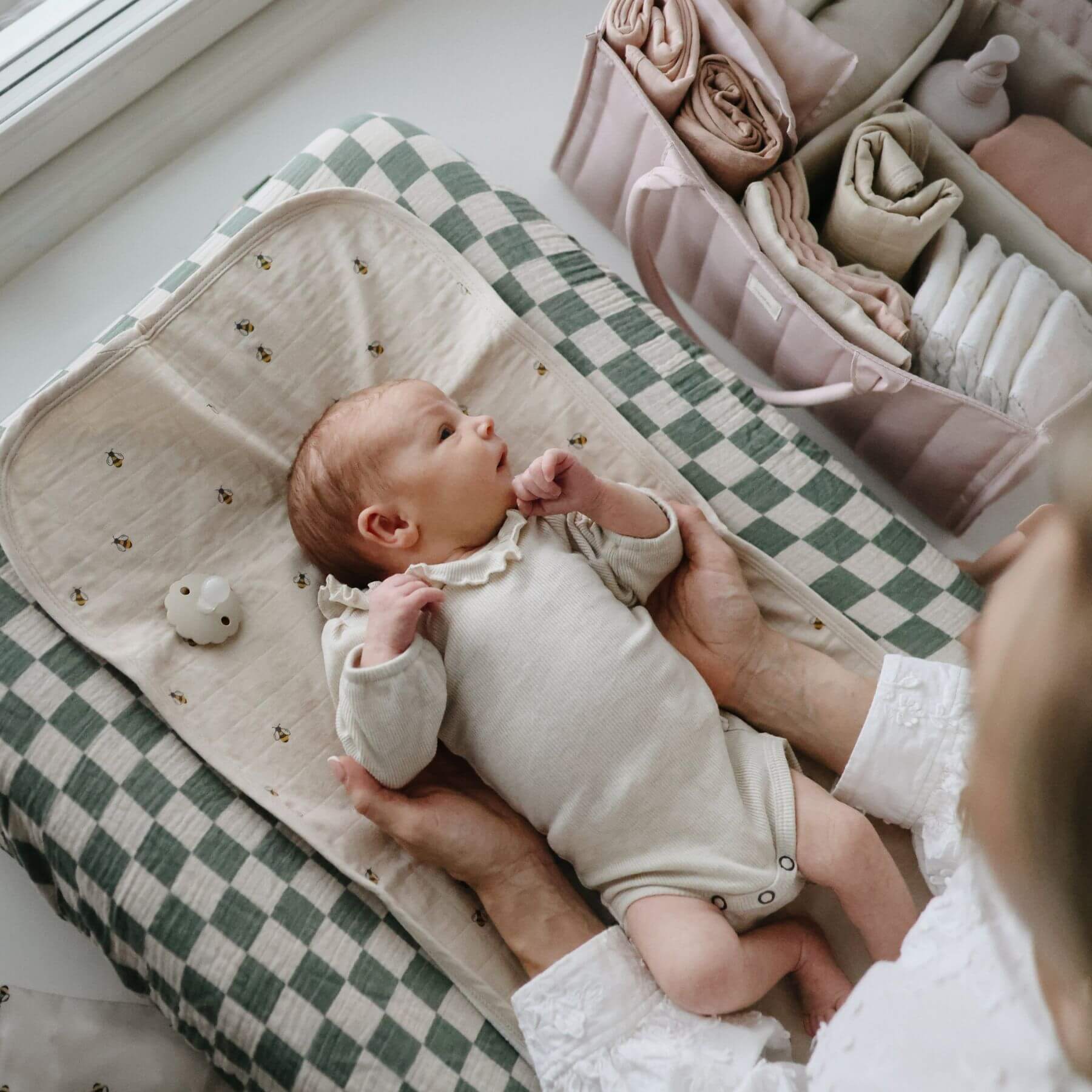 Baby sleeps in a lounge next to Mushie Diaper Caddy