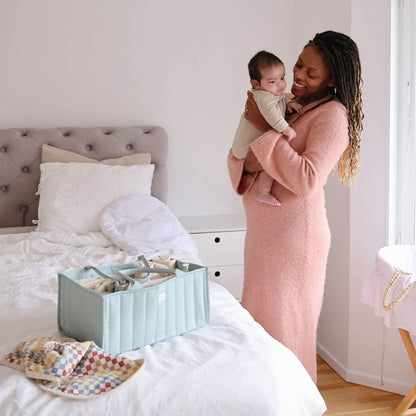 Mom holding a baby next to a bed