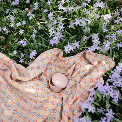 Colorful patterned blanket on grass with small flowers