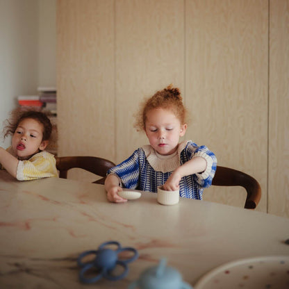 Two children sitting at a table with food container