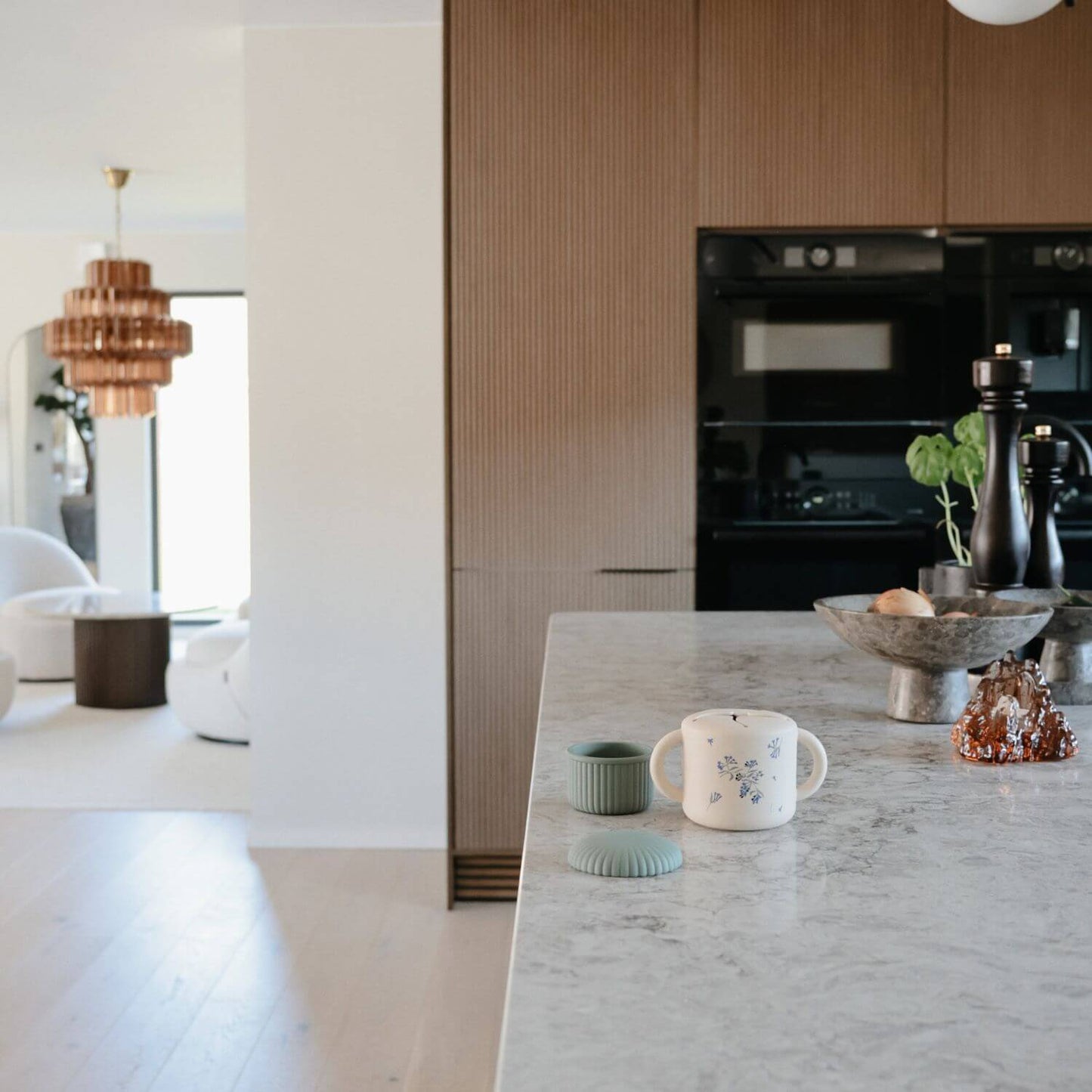Modern kitchen with marble island, black appliances, and decorative items.