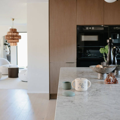 Modern kitchen with marble island, black appliances, and decorative items.