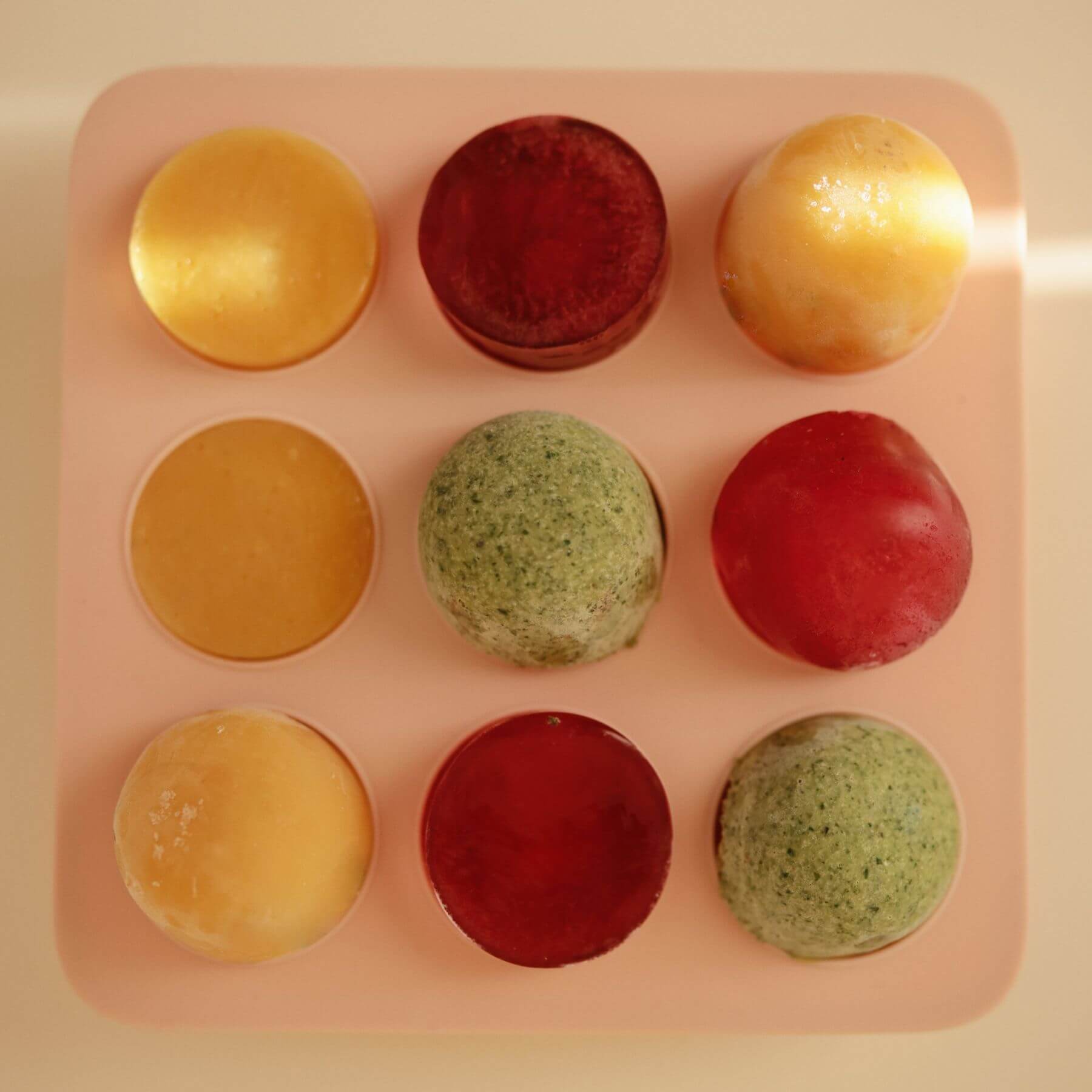 Nine colorful ice creams arranged in a Mushie Baby Food Freezer Tray