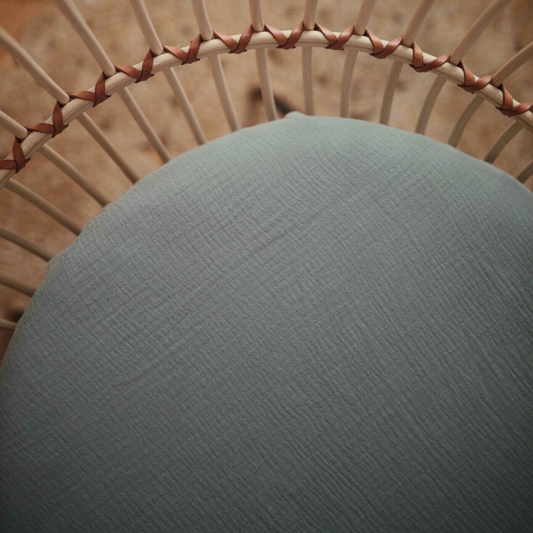 Close-up of a textured green cushion on a wicker chair