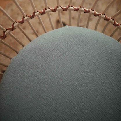 Close-up of a textured green cushion on a wicker chair