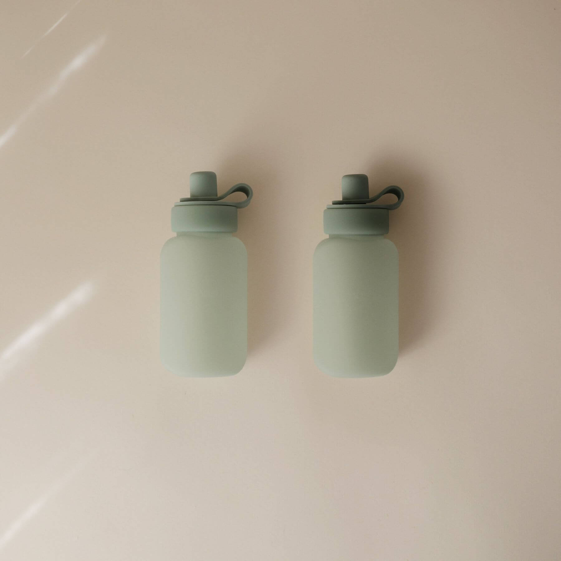 Two Mushie Silicone Puree Pouch on a beige surface