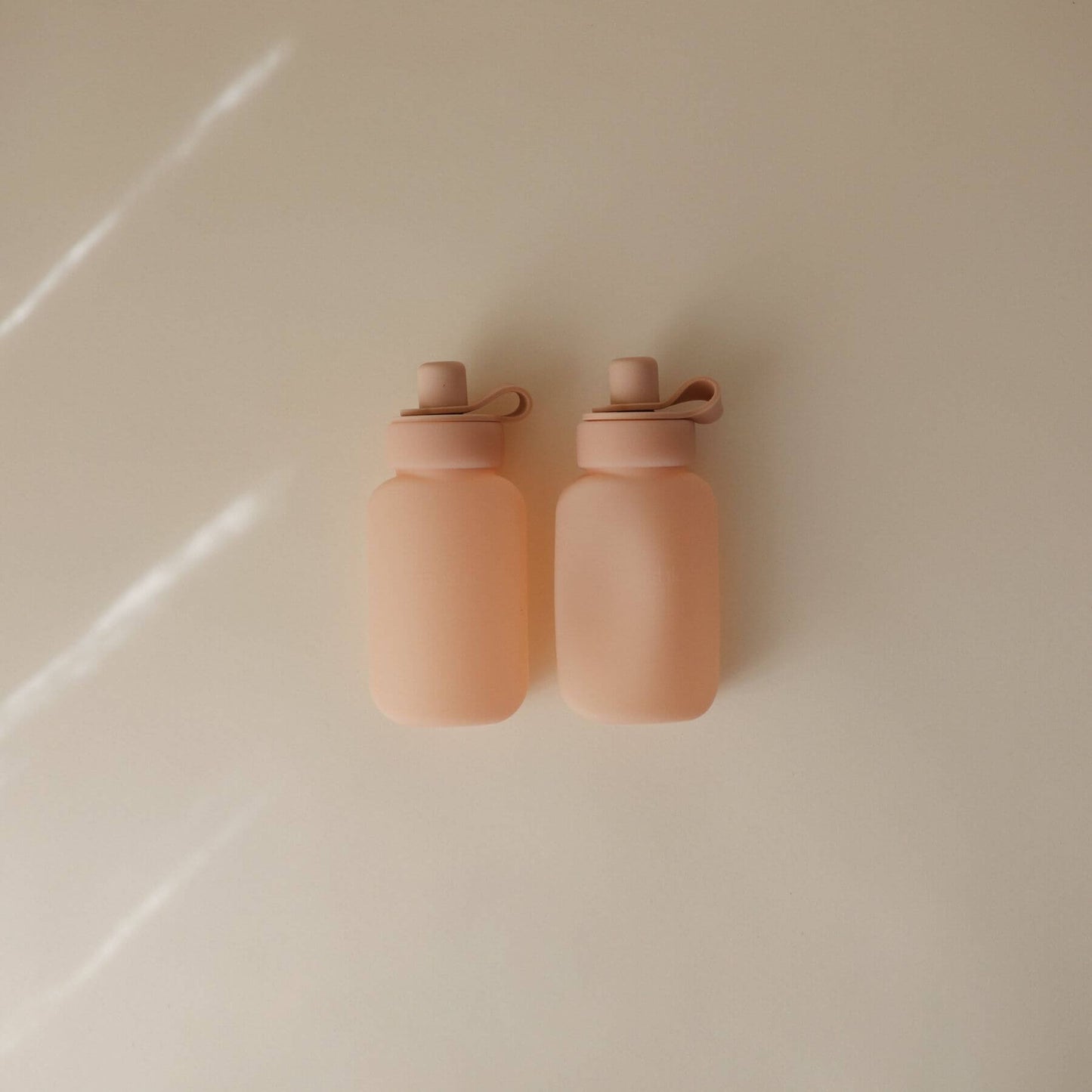 Two Mushie Silicone Puree Pouch on a light beige surface.