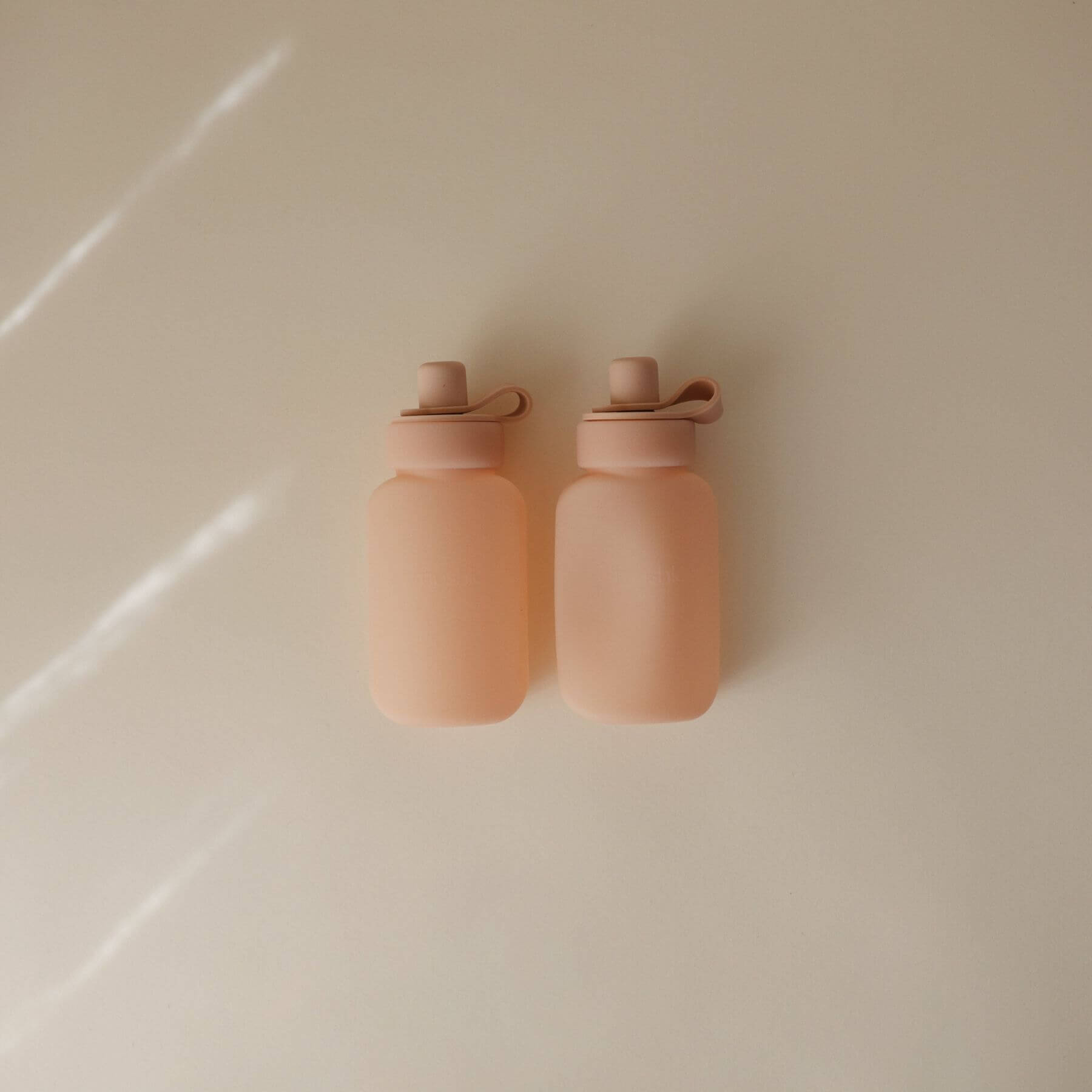 Two Mushie Silicone Puree Pouch on a light beige surface.