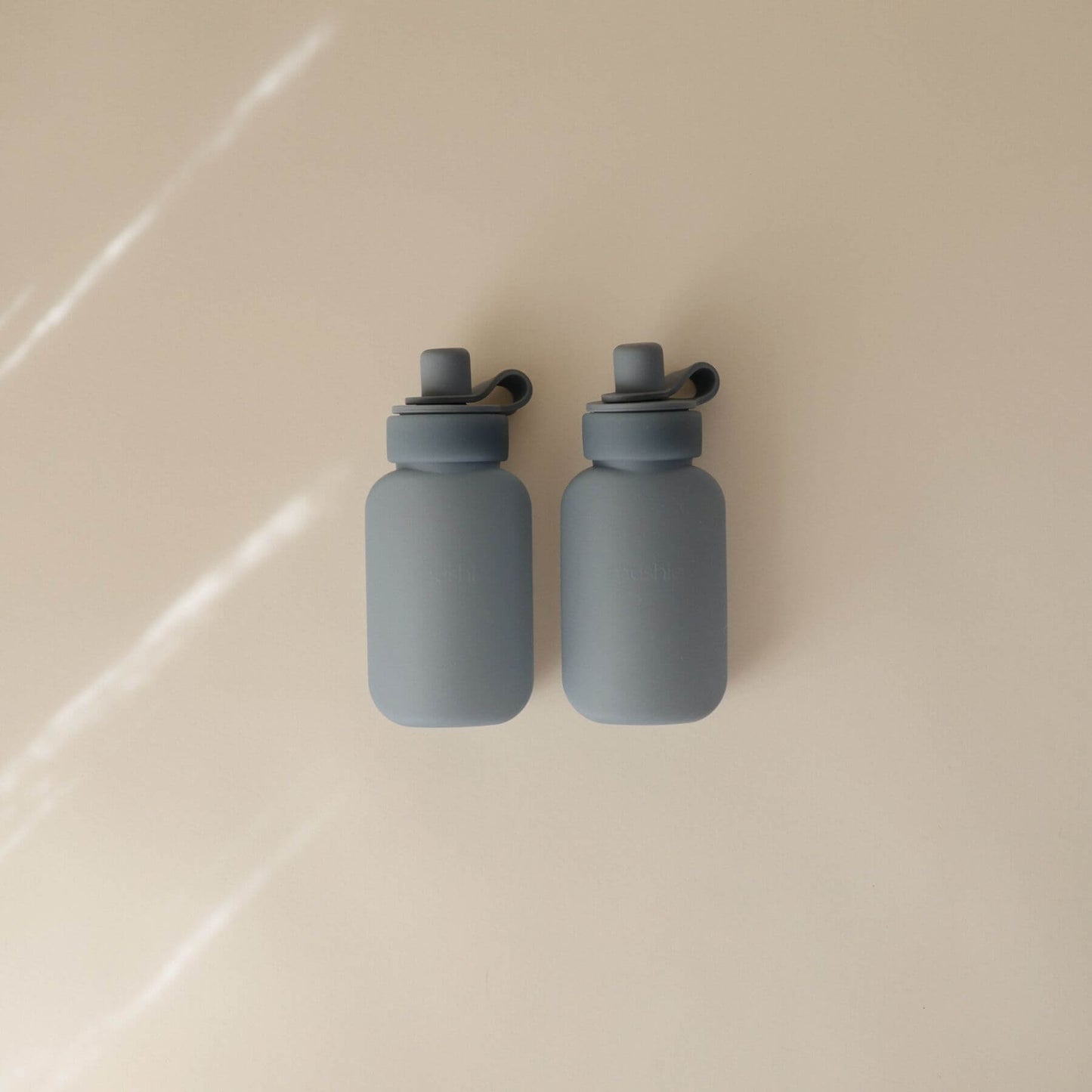 Two Mushie Silicone Puree Pouch on a beige surface