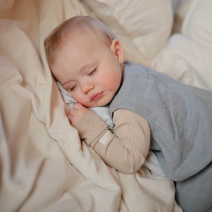 Baby sleeping peacefully in a cozy setting with soft bedding.