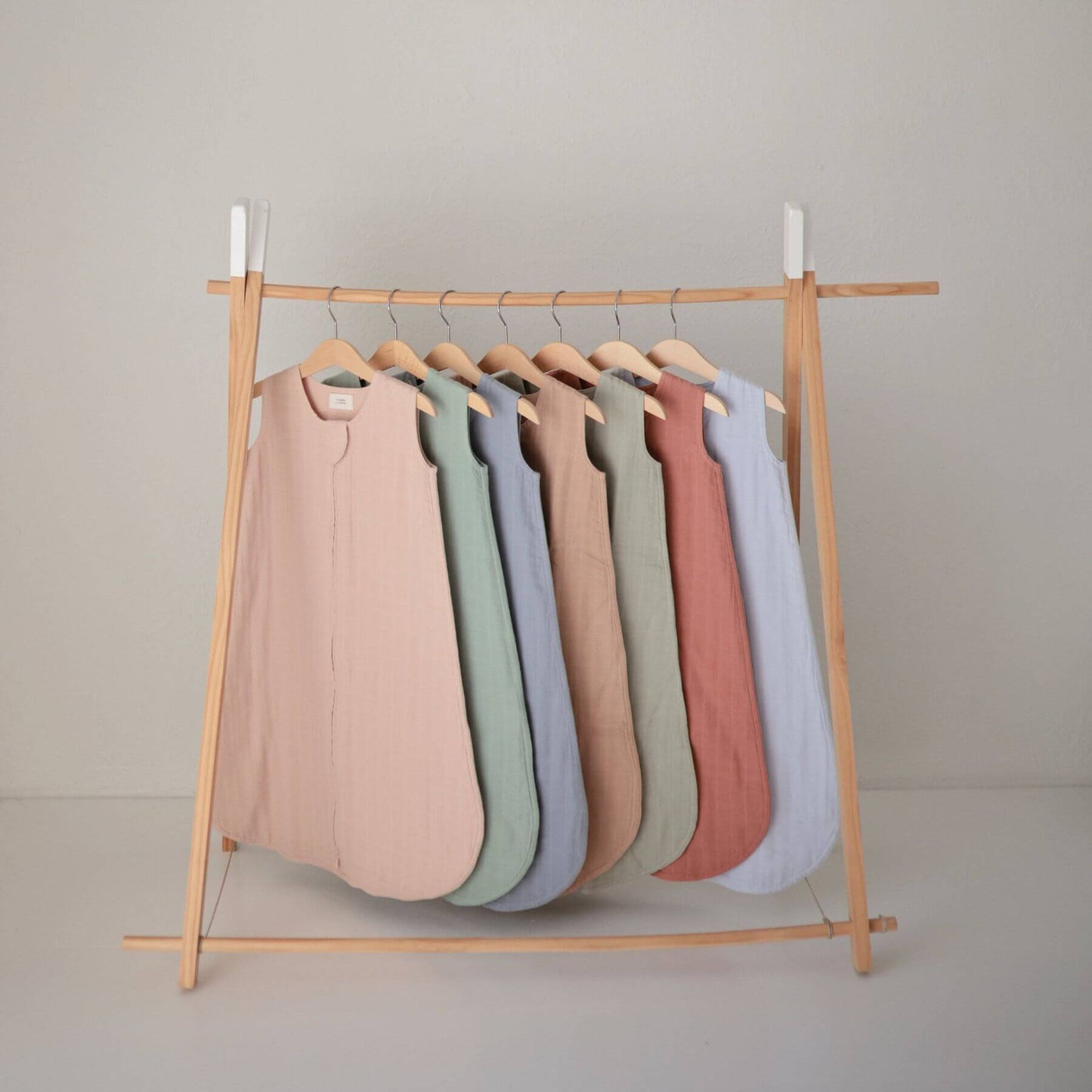 Mushie Organic Cotton Sleep Bags in seven colors, hanging on the shelf