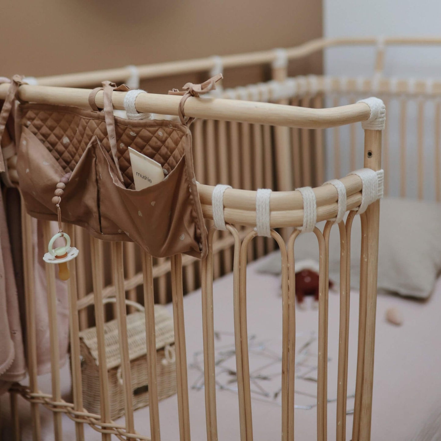 Bamboo crib with baby items including a pacifier and small bag in a nursery setting.