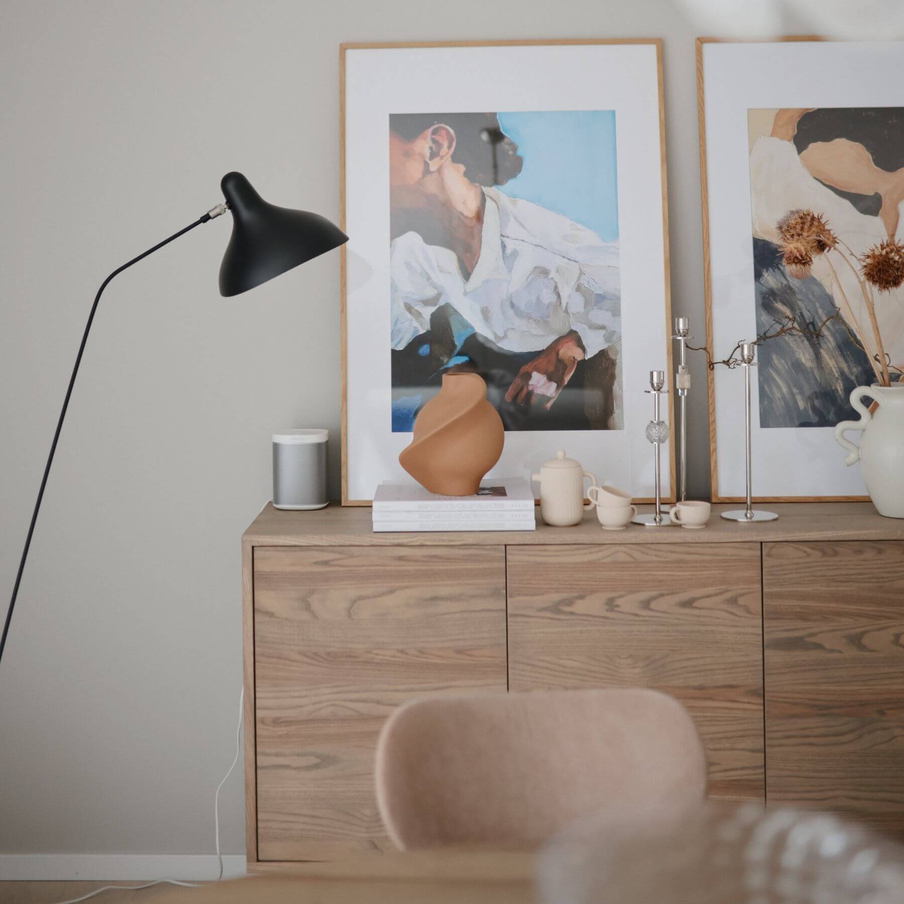 Wooden dresser with decorative items including a black lamp, framed pictures, and a vase.