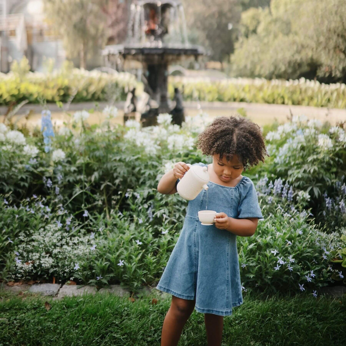 Child in a garden playing Mushie Silicone Tea Play Set