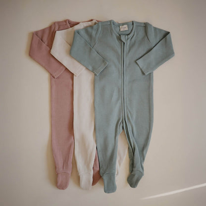 Three Mushie Zipper Pajamas in green, ivory, and blush