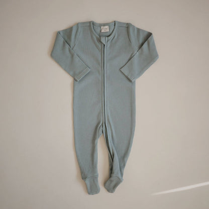 Mushie Zipper Pajama - Green, laid flat on a light beige background.