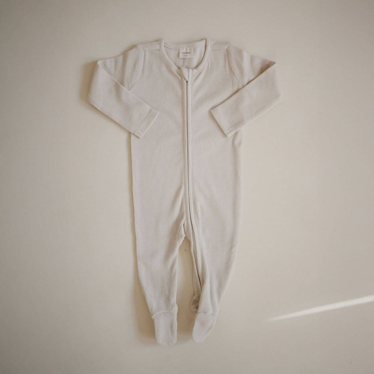 Mushie Zipper Pajama - IVory on a beige background