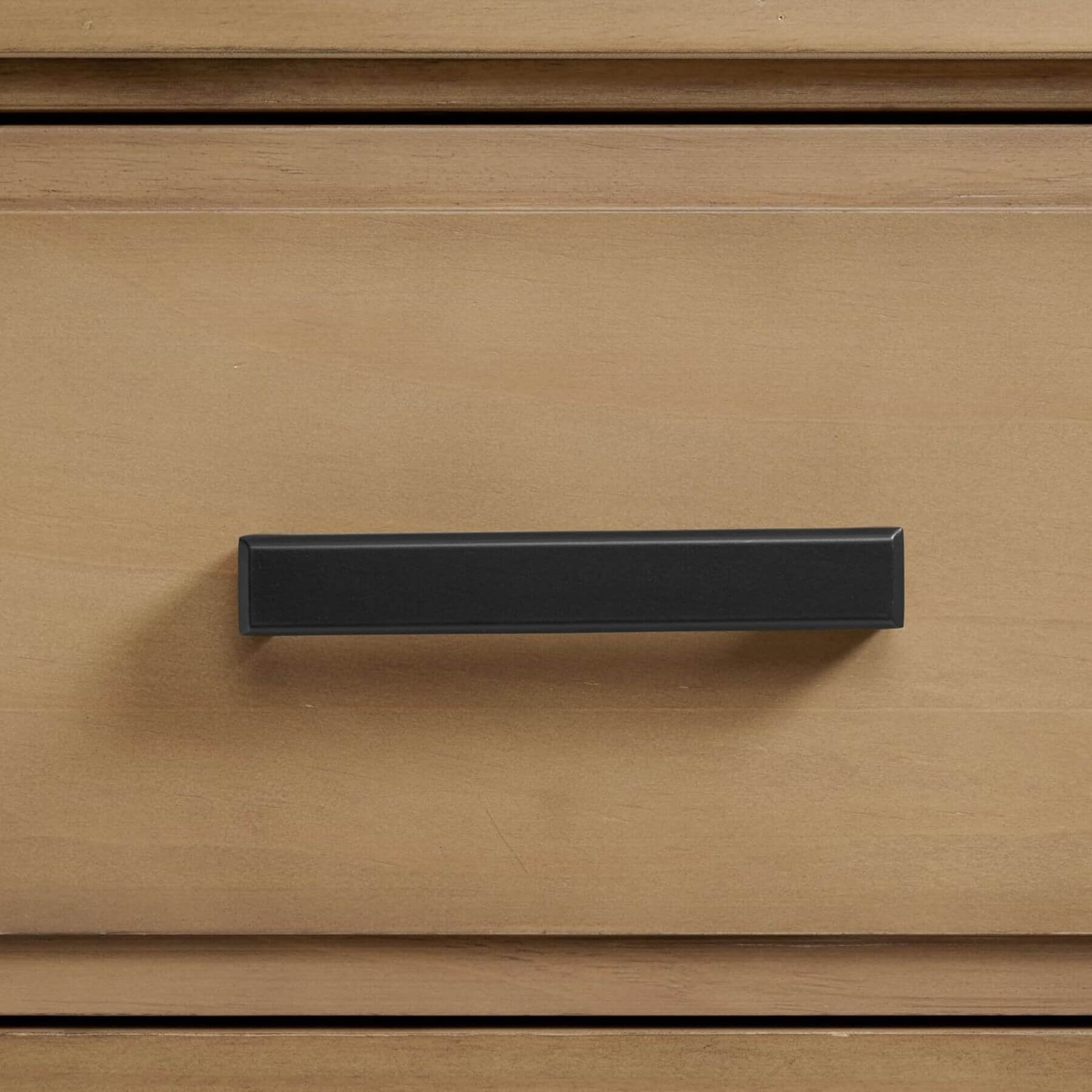 Black cabinet handle on a wooden drawer