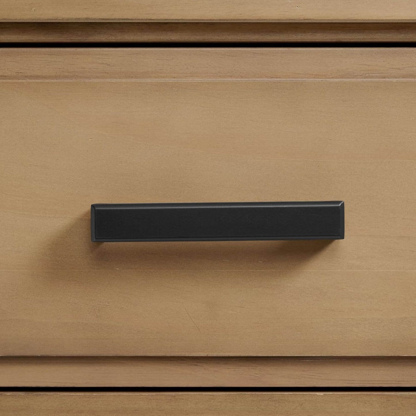 Black cabinet handle on a wooden drawer