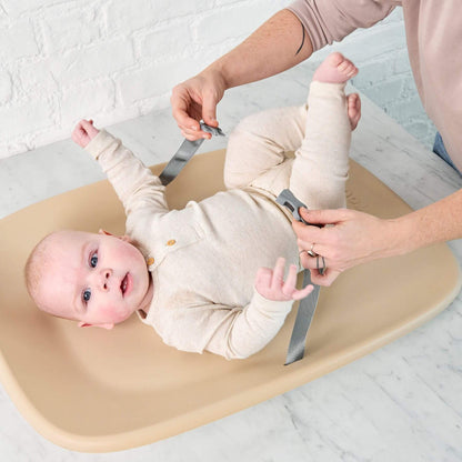 Baby lying on Nattou Diaper Changing Pad Softy Beige with adult hands adjusting straps