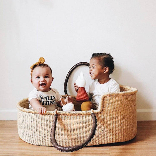 Two Babies Sitting in Plum+Sparrow Natural African Moses Basket Brown Handle