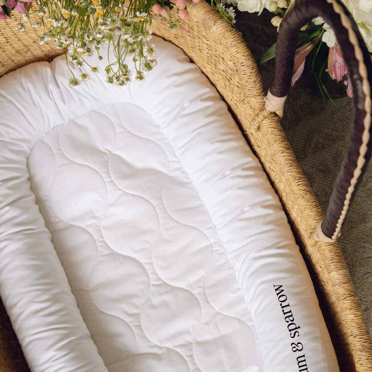 Plum+Sparrow Nest Lounger on a woven basket with flowers.