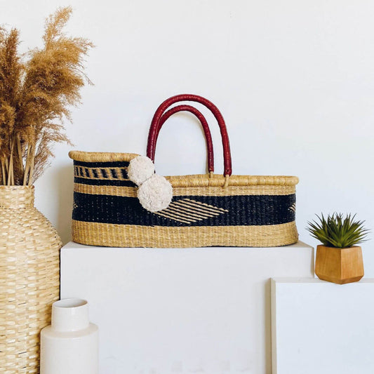 Plum+Sparrow Nightfall African Moses Basket on a white surface with decorative elements.