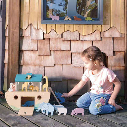 Child playing with Tender Leaf Noah’s Wooden Ark in front of a wooden playhouse.