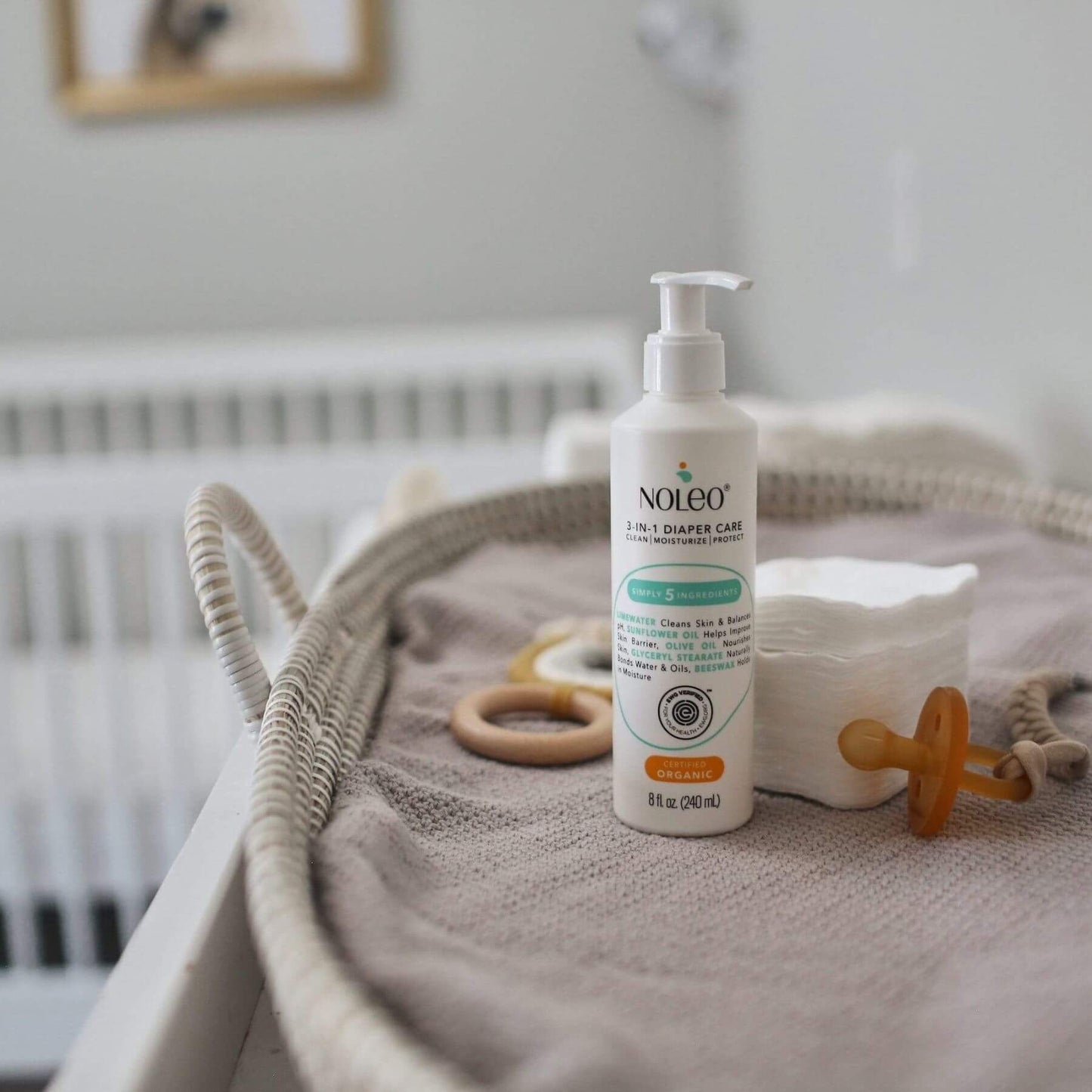 Noleo diaper care product on a textured surface with baby items in a nursery setting