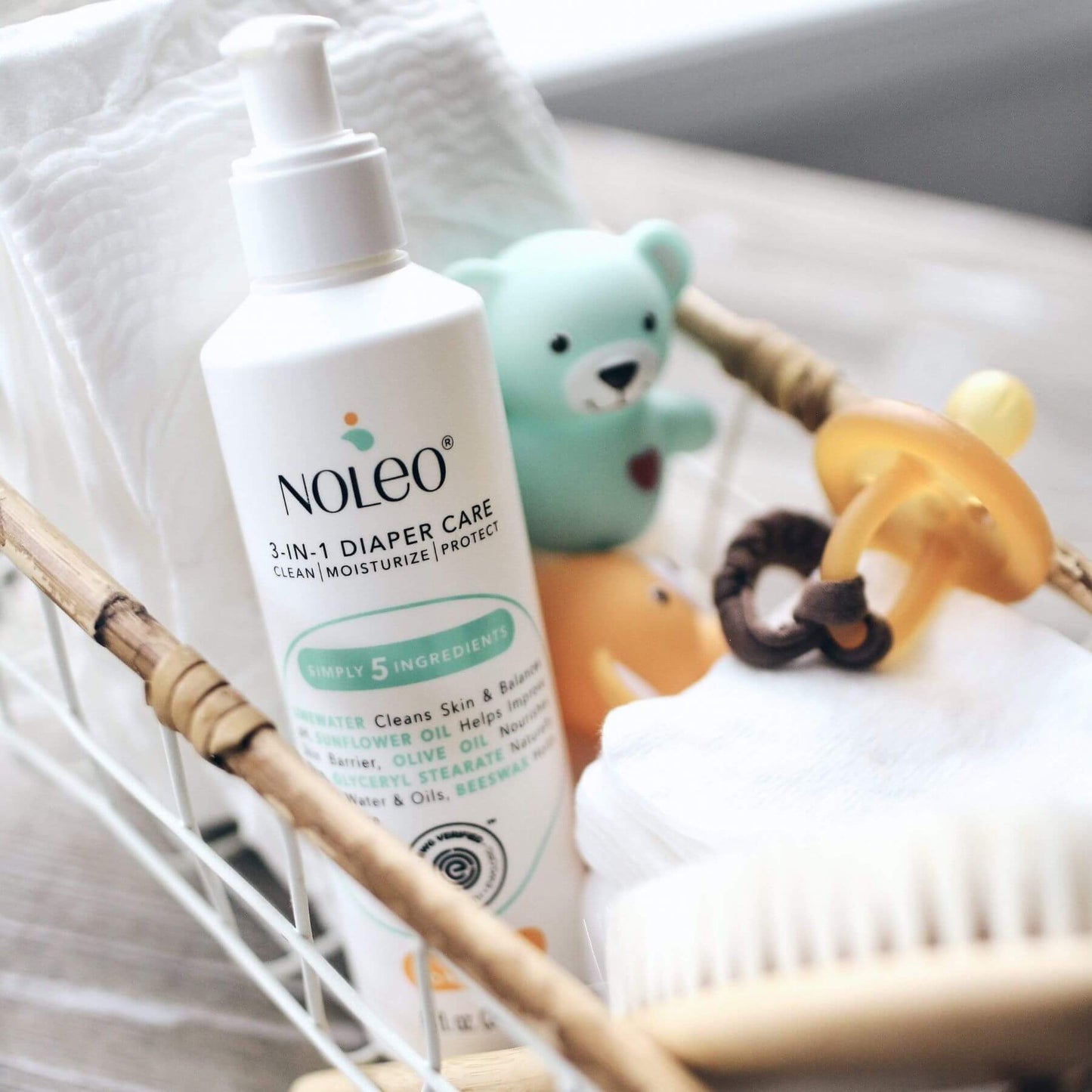 Noleo 3-in-1 diaper care product with baby toys and a pacifier on a white surface