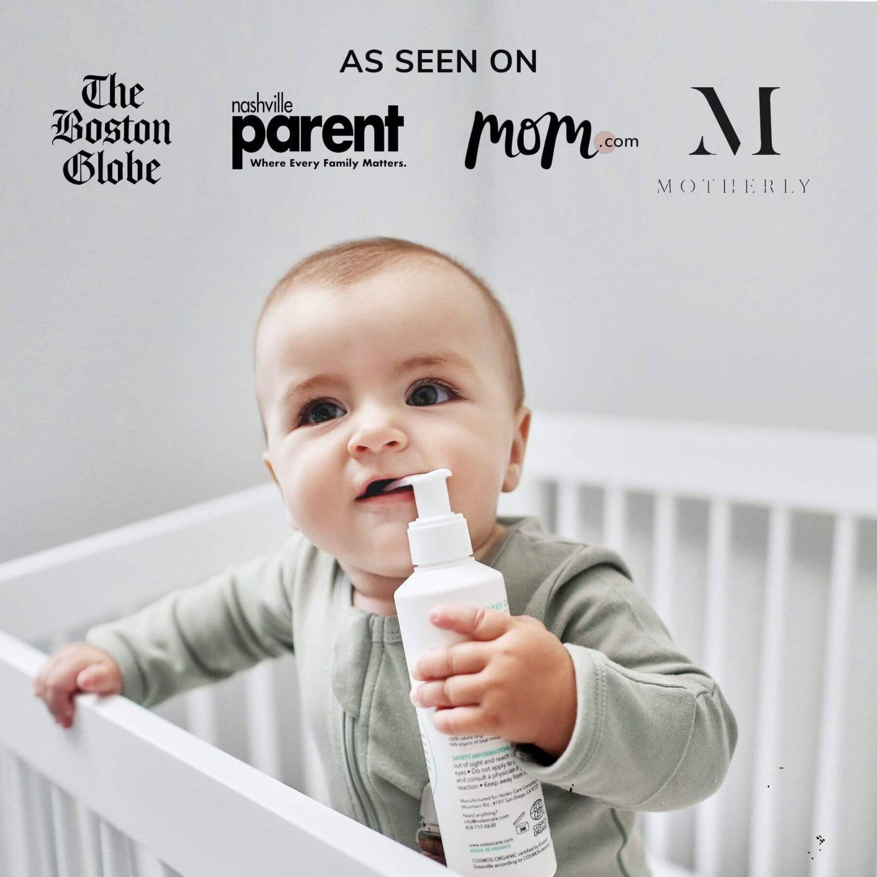 Baby holding a bottle in front of a crib with various media outlet logos above.