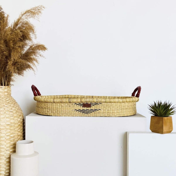 Plum+Sparrow Oak Changing Basket on a white surface, surrounded by decorative items.