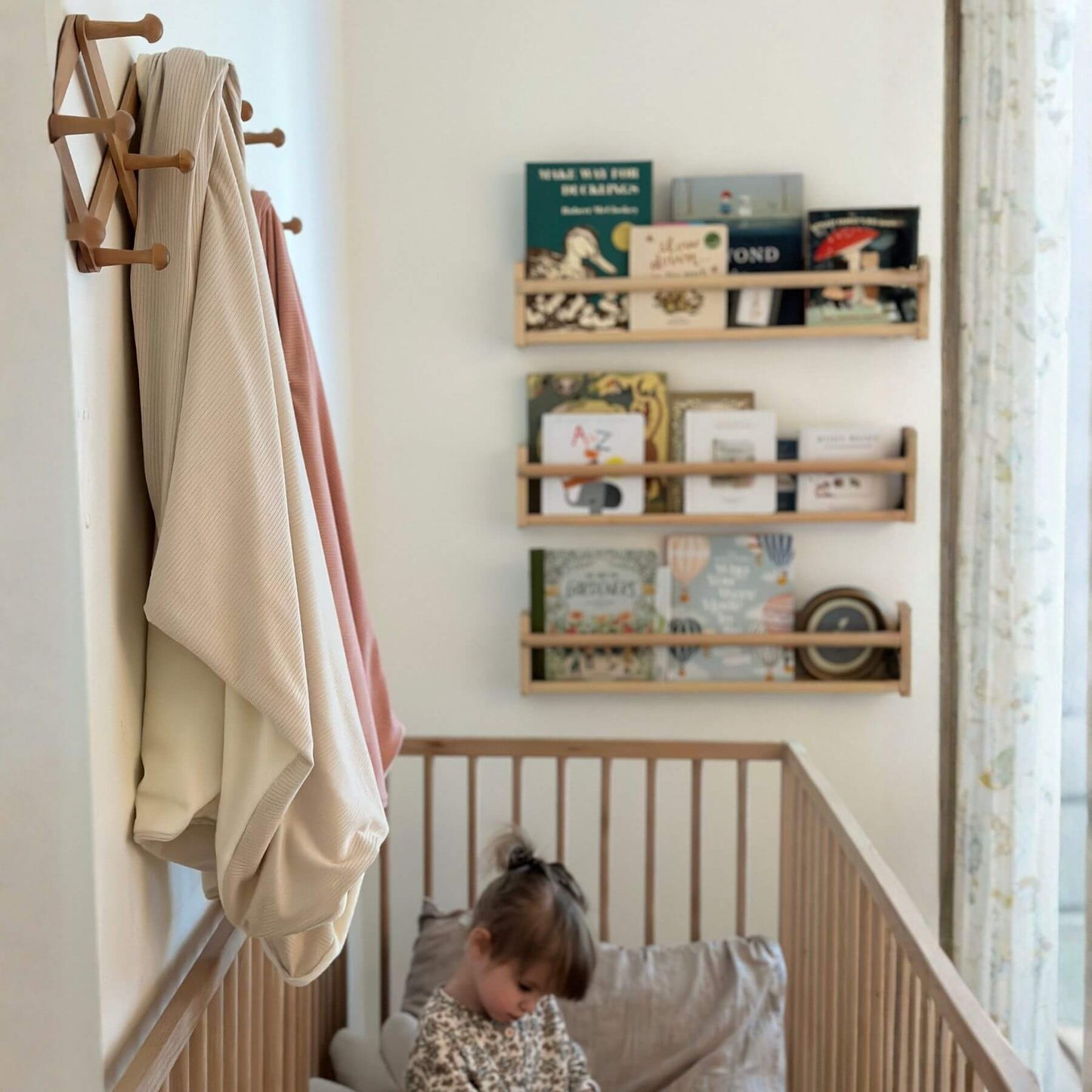 Nursery room with wooden shelves, books, and a child in a crib.