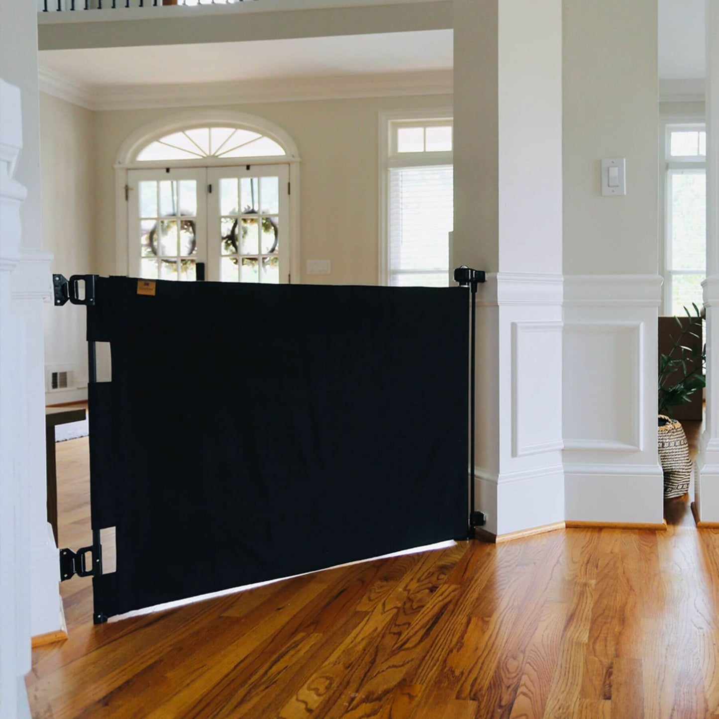 Crafted Gates Co. Oil Waxed Canvas Pet Safety Gate - Black in a home interior with wooden floor and white walls.