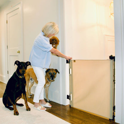 Woman opening Crafted Gates Co. Oil Waxed Canvas Pet Safety Gate - Sand with two dogs waiting on either side.