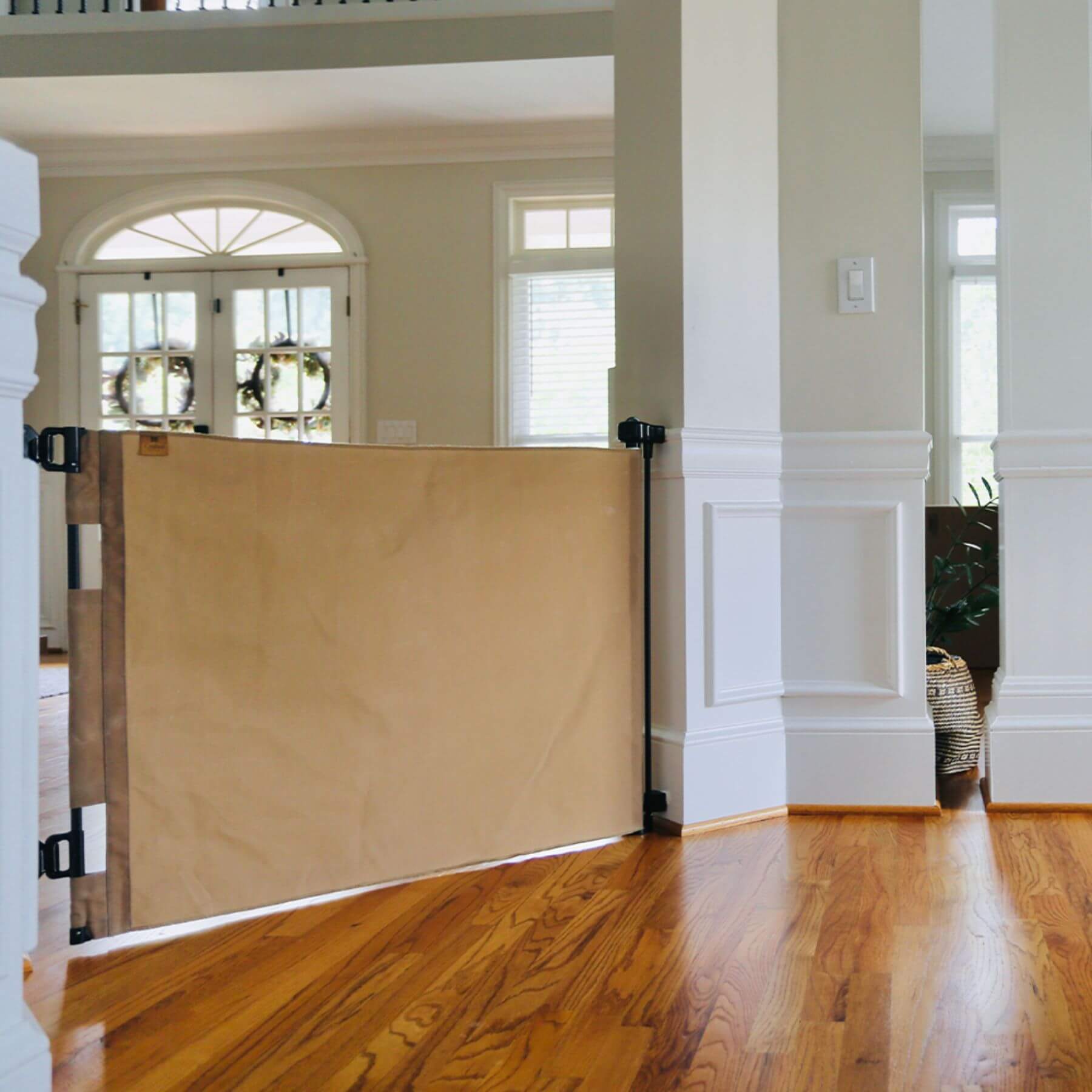 Crafted Gates Co. Oil Waxed Canvas Pet Safety Gate - Tan in a home interior with wooden floor and white walls.