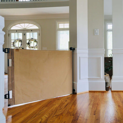 Crafted Gates Co. Oil Waxed Canvas Pet Safety Gate - Tan in a home interior with wooden floor and white walls.