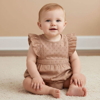 Baby sitting on a carpet wearing Makemake Organics Organic Eyelet Flutter Romper - Clay Eyelet