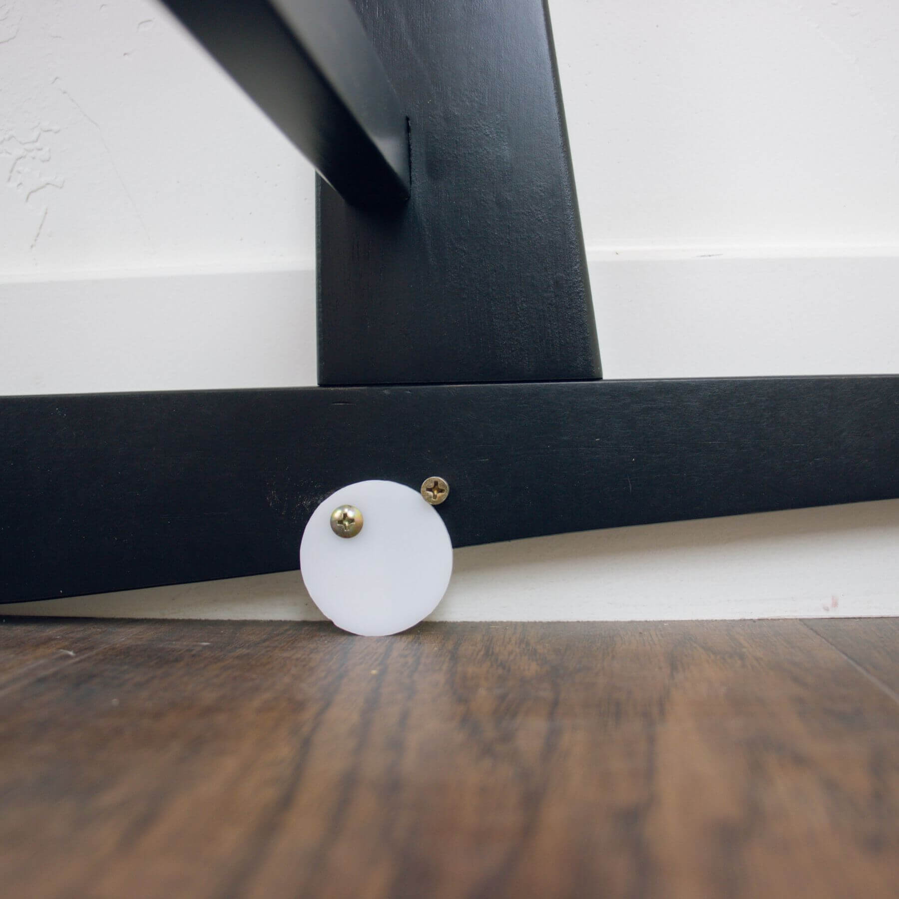 Close-up of Plum+Sparrow Original Rocking Moses Bassinet Stand with brake Black on a wooden floor.
