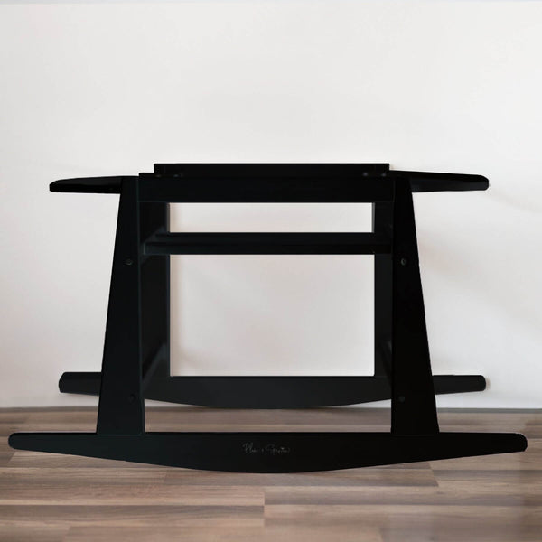 Plum+Sparrow Original Rocking Moses Bassinet Stand with brake Black on a wooden floor with a white wall background