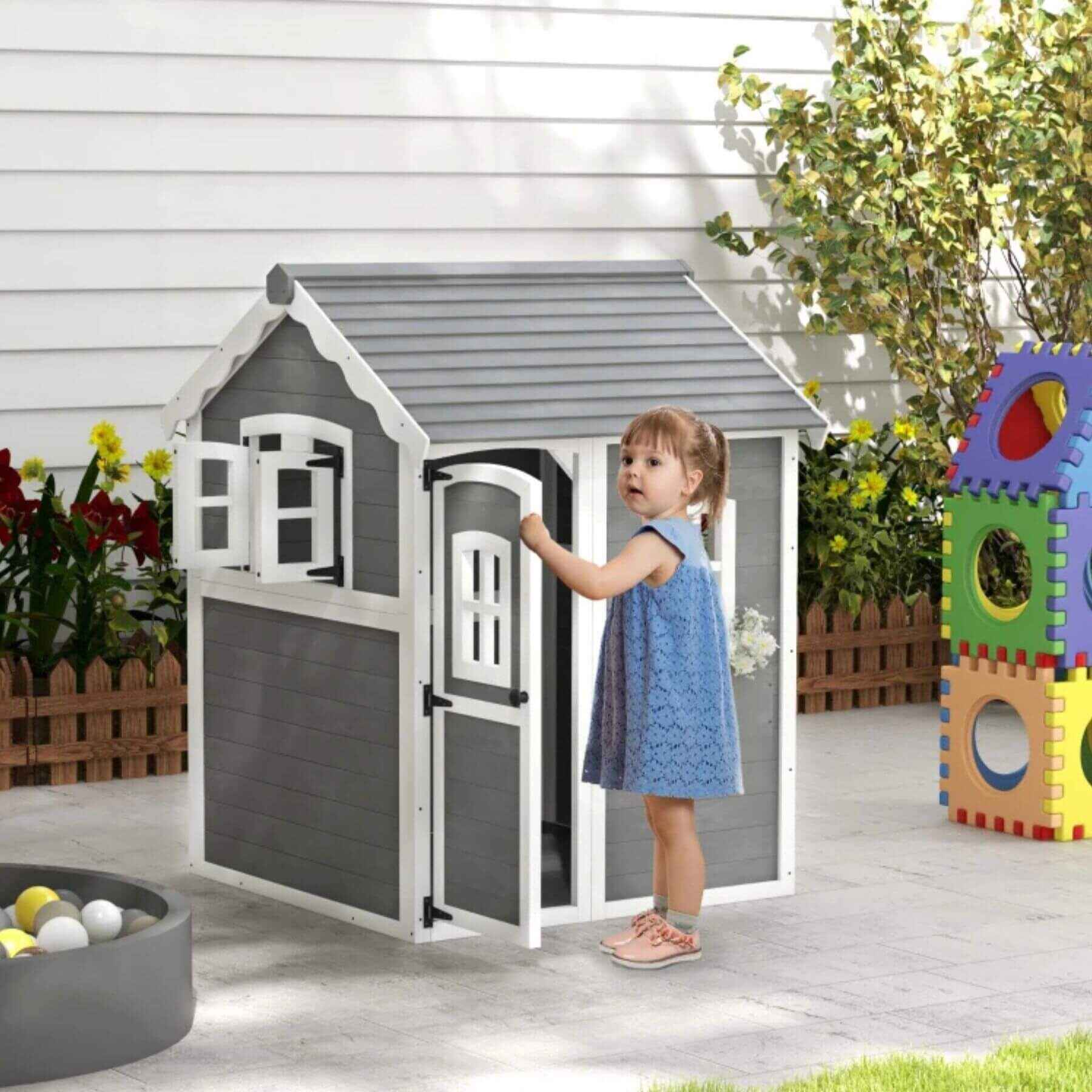 Girl Holding the Door of Outsunny Outdoor Wooden Playhouse for Kids Gray
