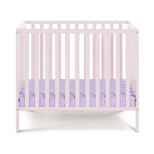 Palmer 3-in-1 Convertible Mini Crib Pastel Pink with a purple mattress on a white background