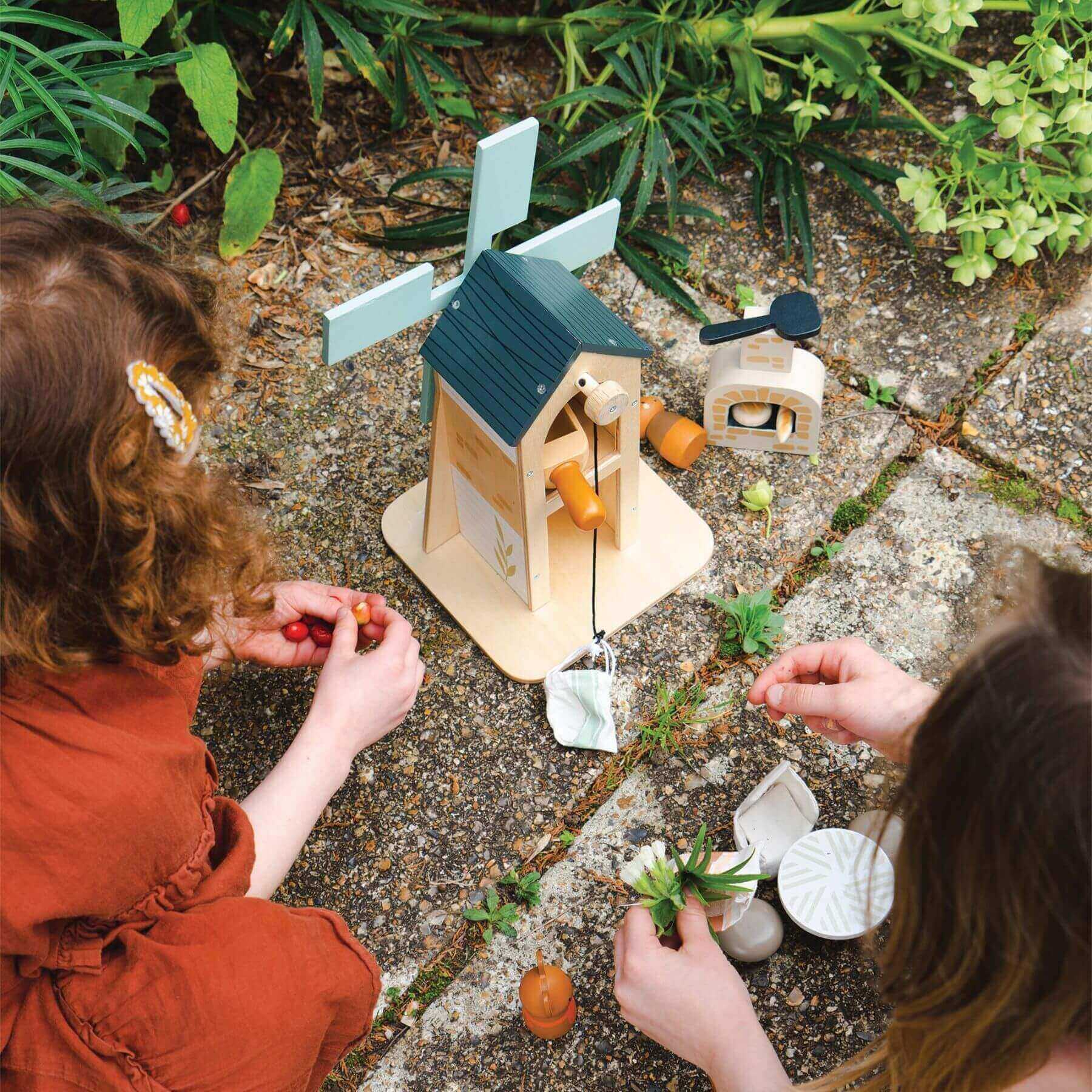 Two children playing with Tender Leaf Penny Windmill outdoors.