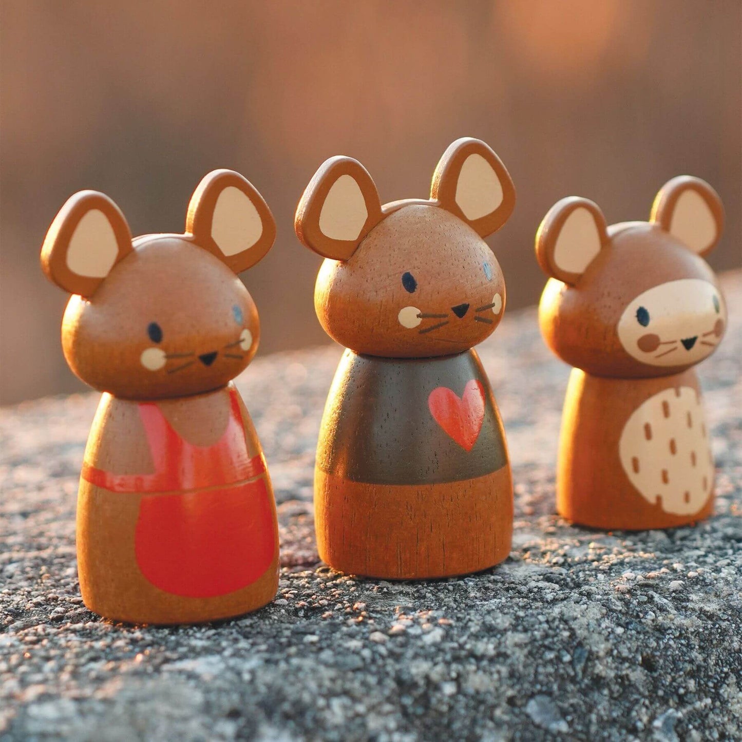 Three wooden mouse figurines with different designs on stone surface