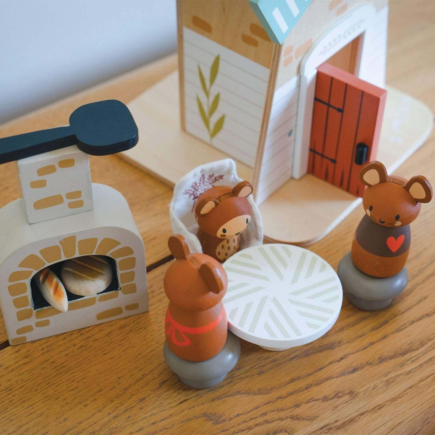 Wooden toy set with animal figures and a small house on a wooden surface