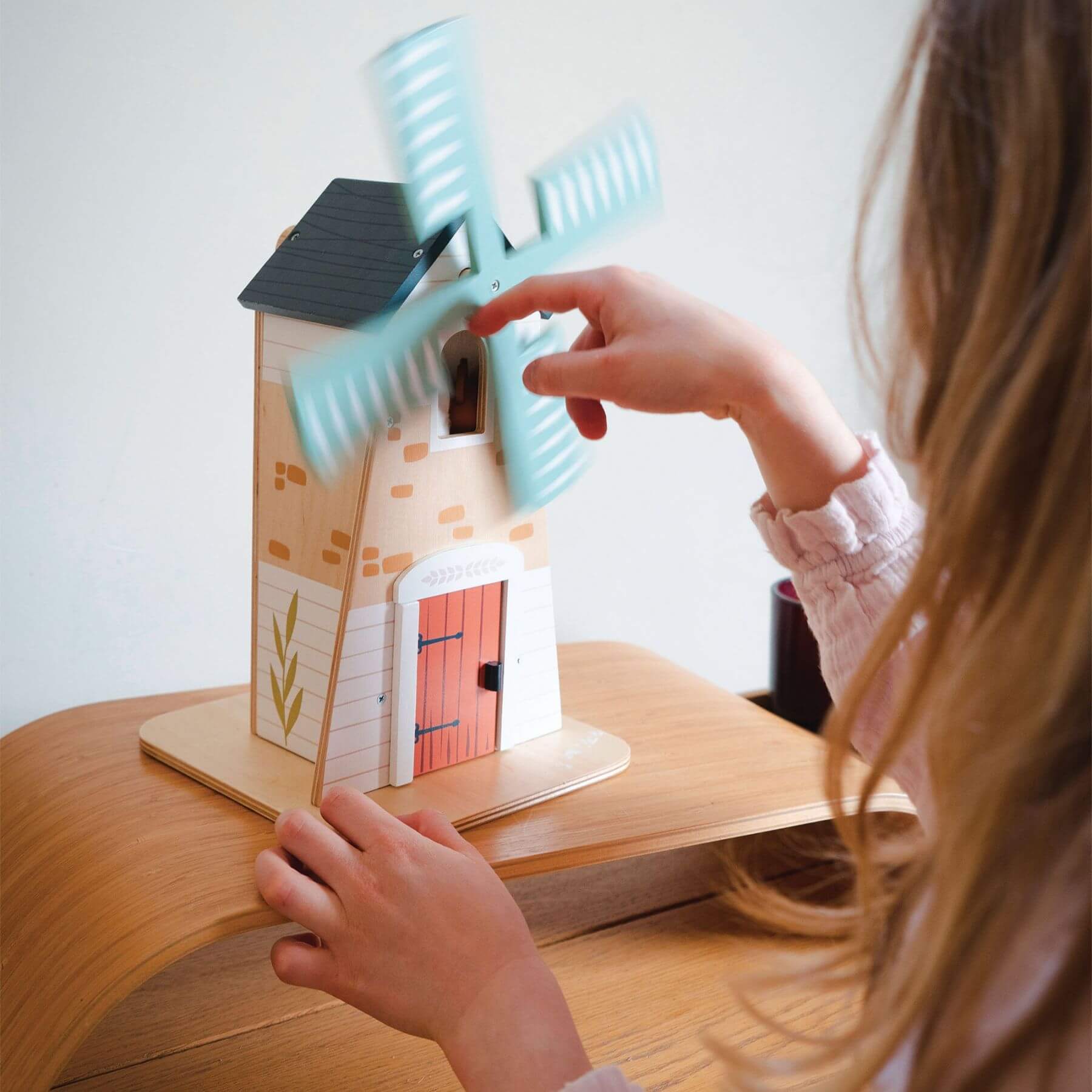 Child playing with Tender Leaf Penny Windmill on a wooden surface