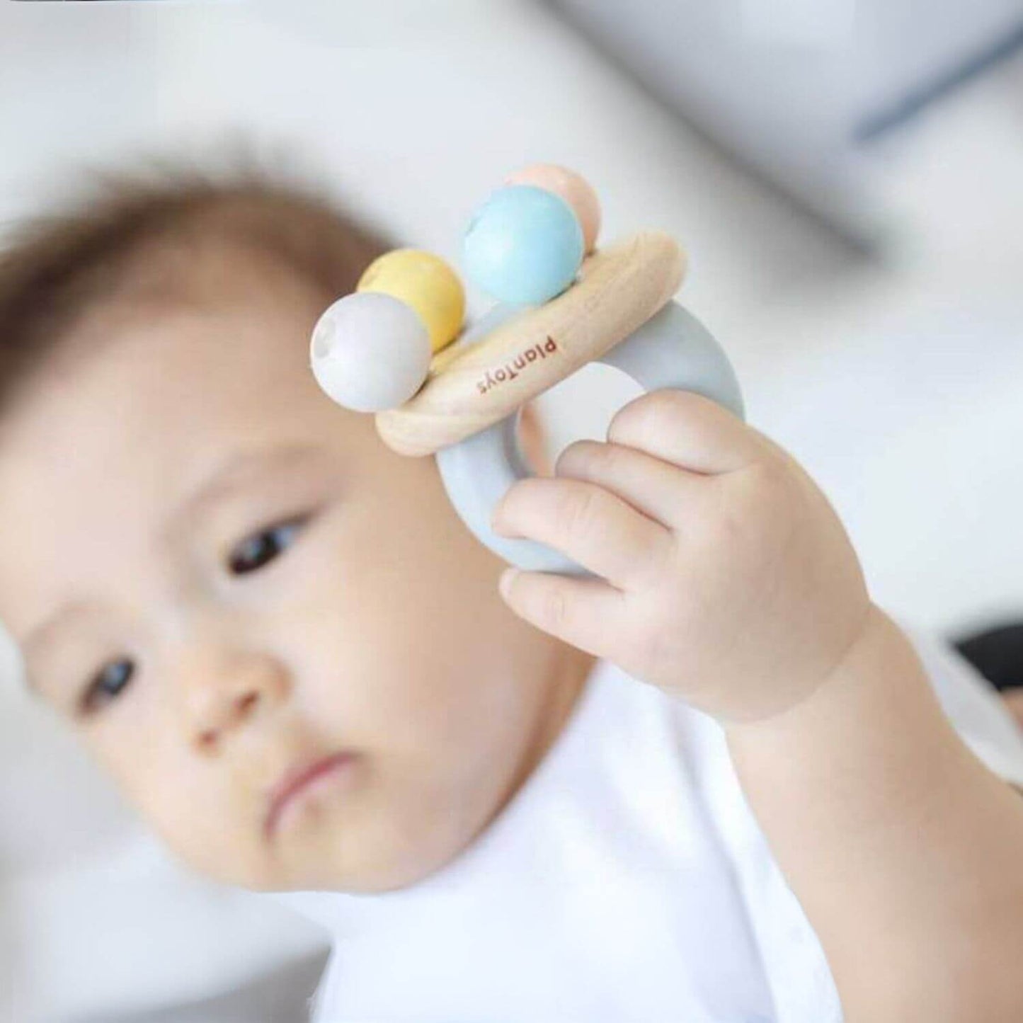 Baby Holding PlanToys Bell Rattle