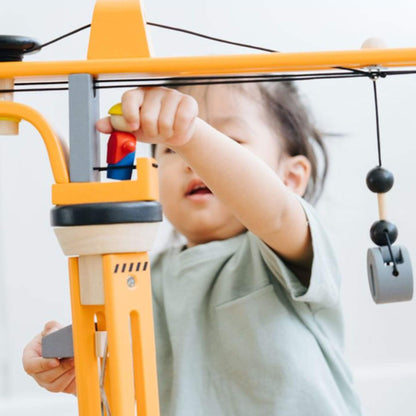 Child playing with PlanToys Crane Set against a white background