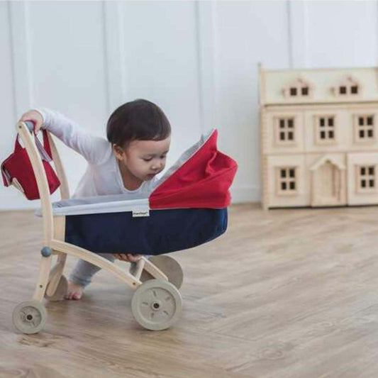 Child playing with PlanToys Doll Stroller on a wooden floor
